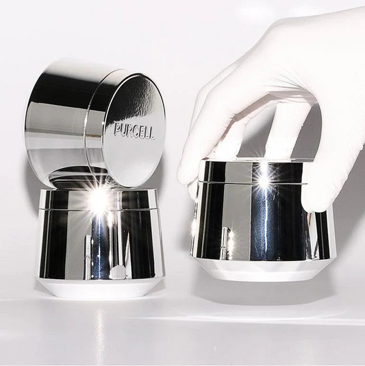 Purcell Pixcell Biom™ After Rebooting Cream 50ml – Hand hält schwarzen Zylinder mit Silberdeckel vor Weiß