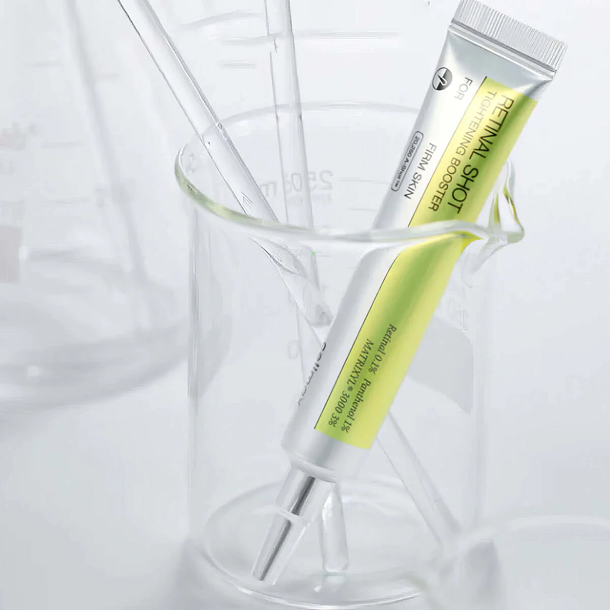 Celimax The Vita-A Retinal Shot Tightening Booster 15ml – klare Tube mit gelbgrünem Inhalt neben Laborbecher und Glasröhrchen