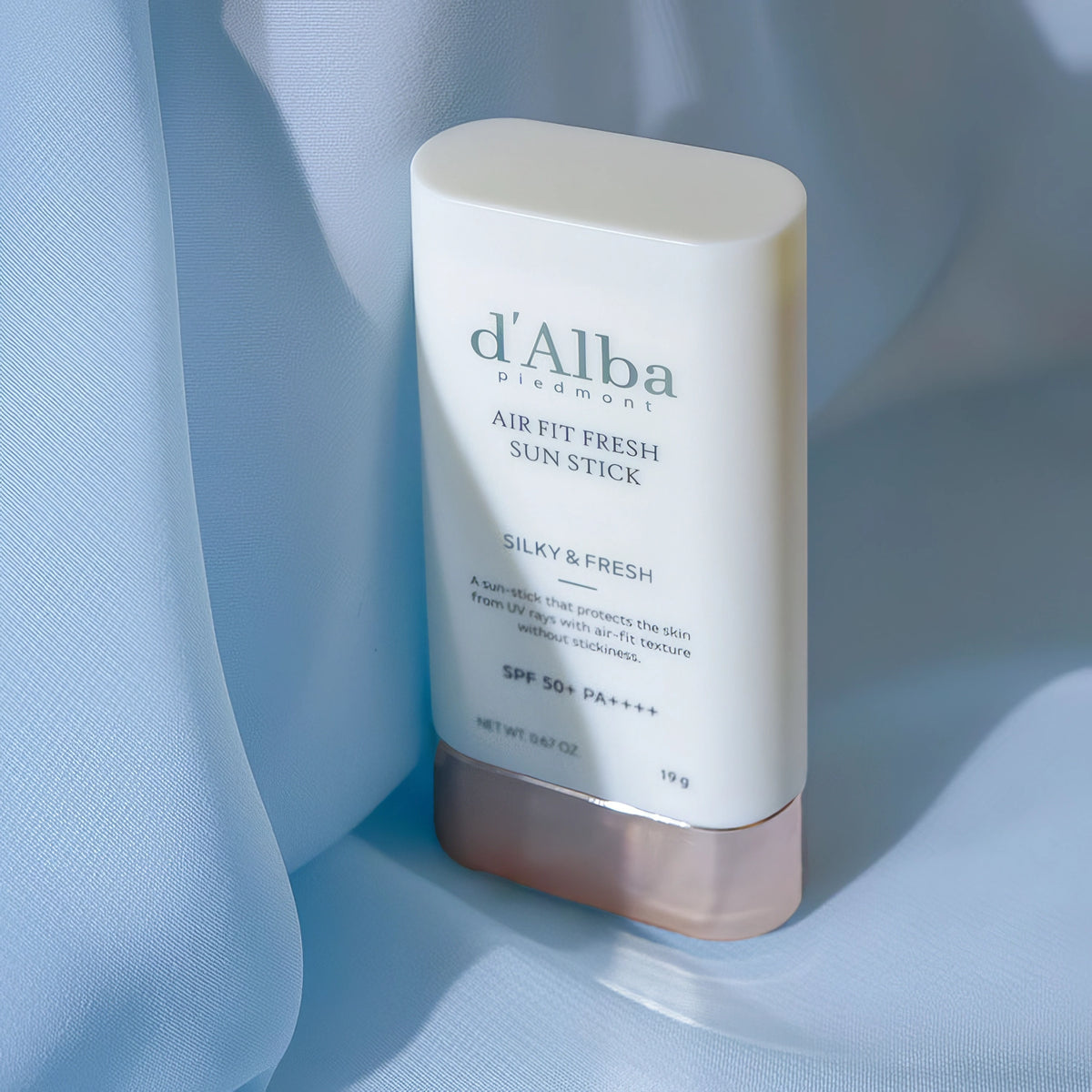 d'Alba Air Fit Fresh Sun Stick SPF50+/PA++++ 19g – weißer Stick mit goldfarbener Kappe vor pastellfarbenem Grund
