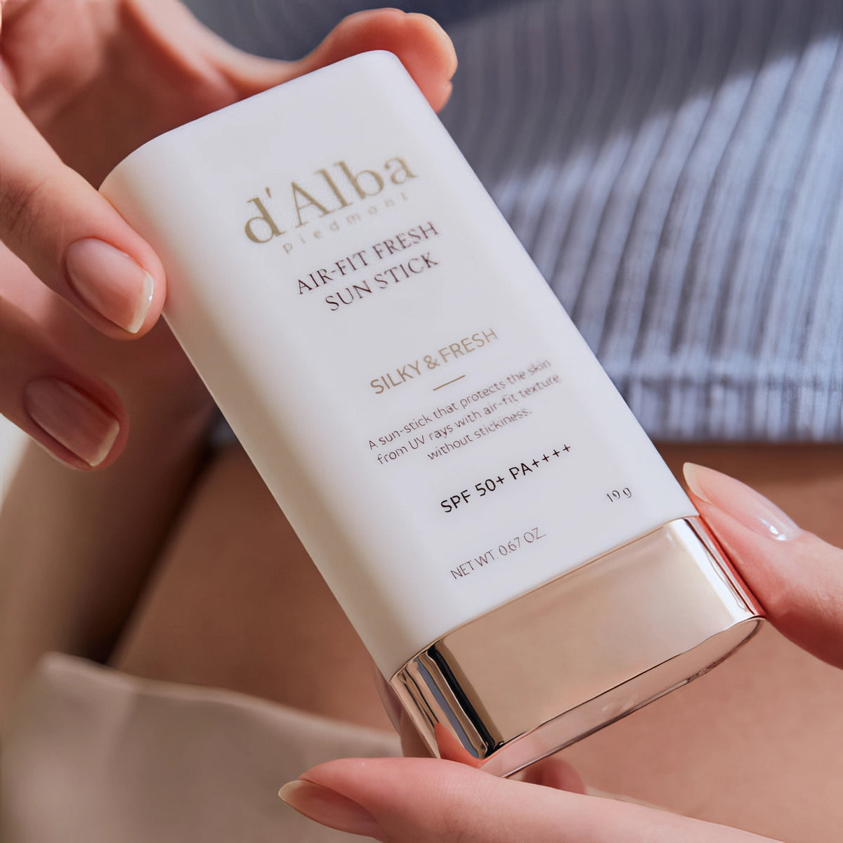 d'Alba Air Fit Fresh Sun Stick SPF50+/PA++++ 19g – Hand hält den weißen Sonnenstick mit goldener Kappe