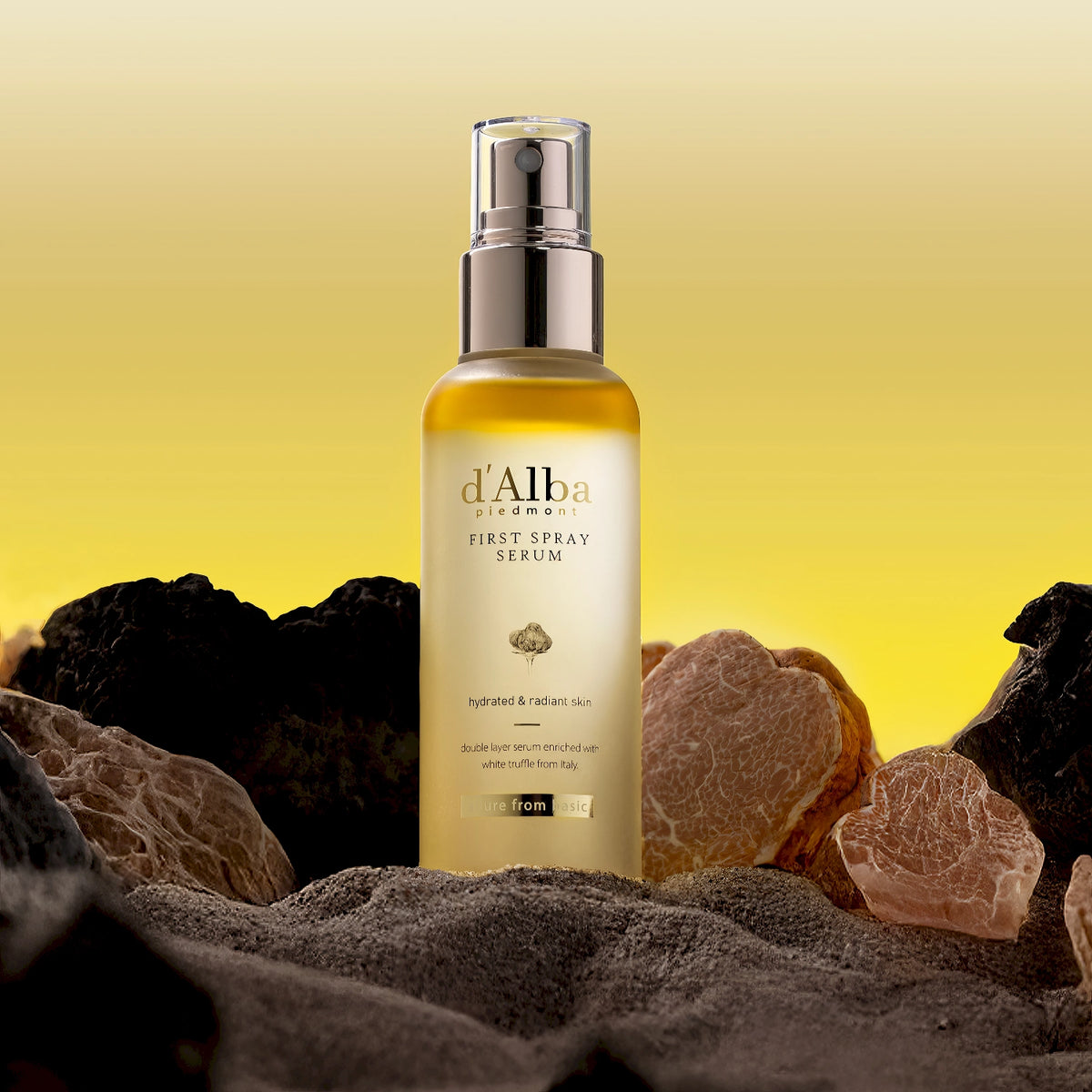 d'Alba White Truffle First Spray Serum 100ml – goldfarben schimmernde Sprühflasche auf porösem Vulkangestein