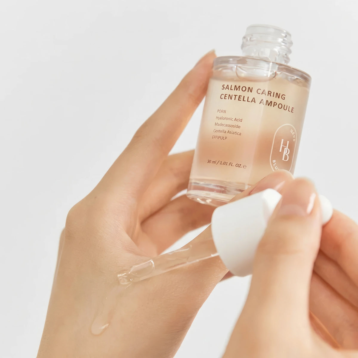 Heveblue Salmon Caring Centella Ampulle 30ml – transparente Flasche mit weißer Kappe, von einer Hand gehalten