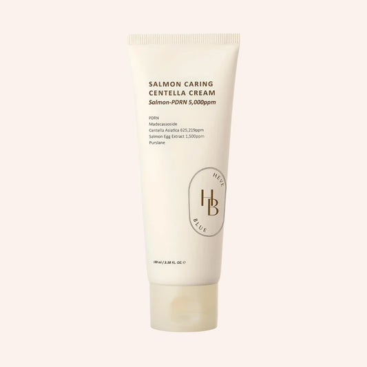 Heveblue Salmon Caring Centella Cream 100ml – weiße Tube mit braunem Etikett und Fisch-Illustration auf Schwarz