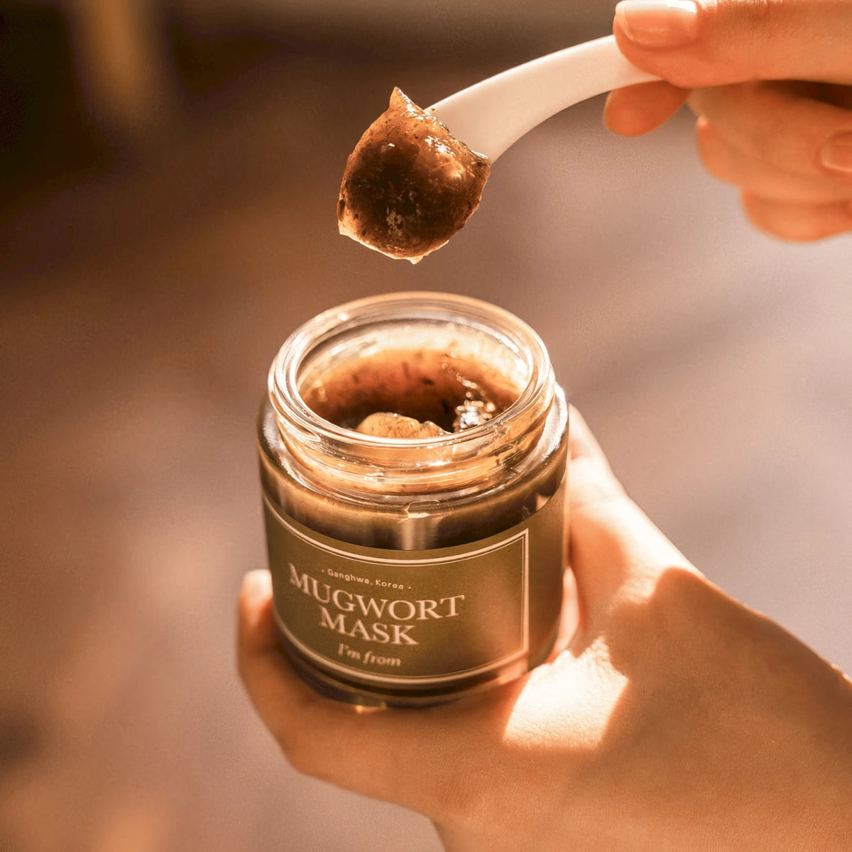 I'm From Mugwort Mask 110g – transparenter Tiegel mit weißem Deckel und dunklem Inhalt, von einer Hand seitlich gehalten