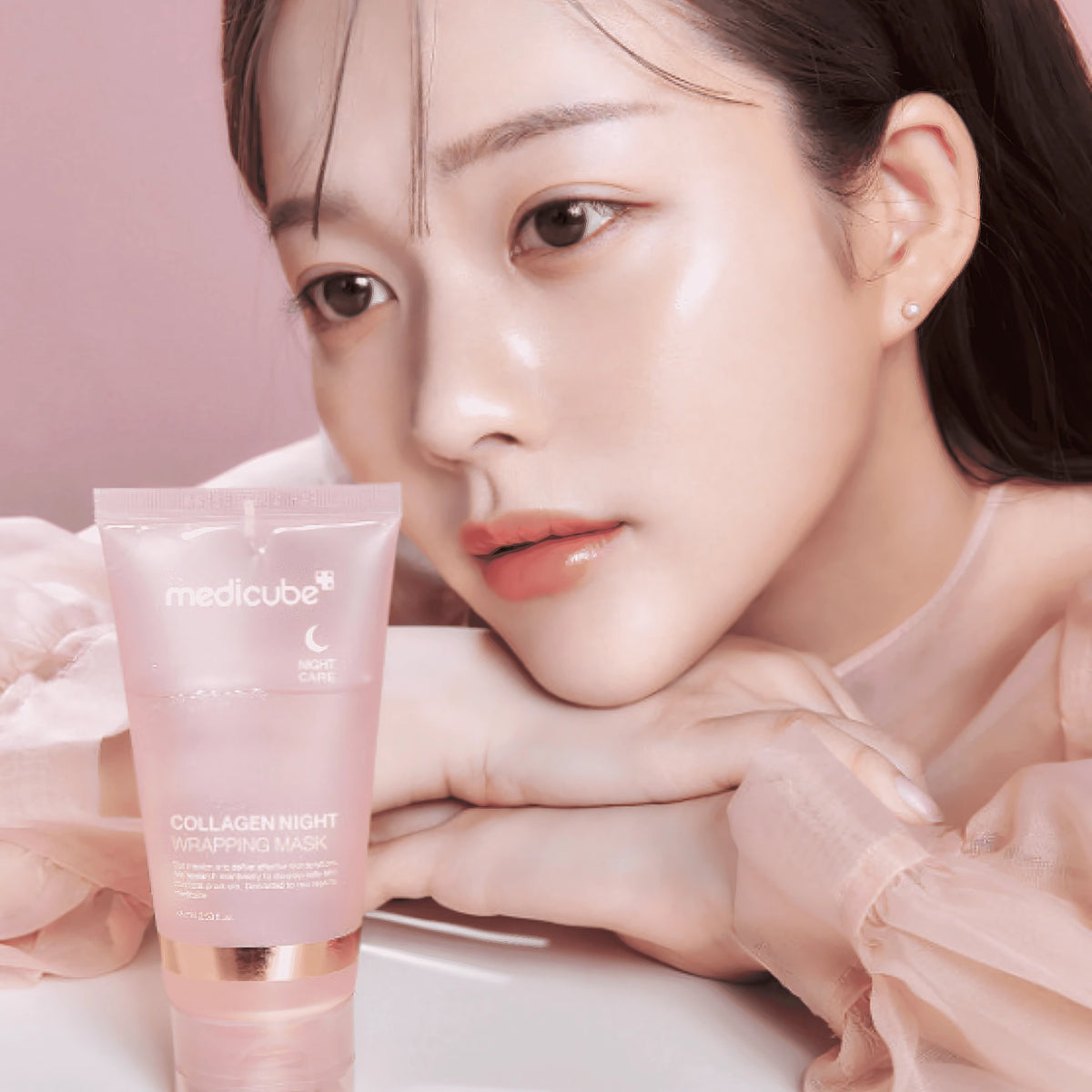 Medicube Collagen Night Wrapping Mask 75ml – Nahaufnahme einer Tube mit weiß-rosa-schwarzem Etikett auf Rosa