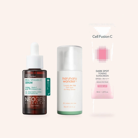 „Tone Perfect“ gegen Pigmentierungen – Vitamin-C-Serum, Tranexamsäure-Serum und getönter Sonnenschutz nebeneinander auf zartrosa Grund